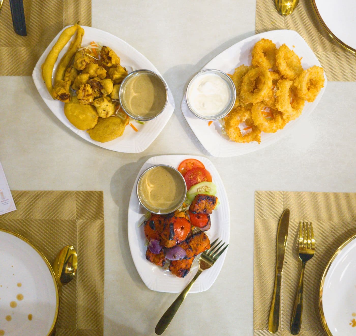 Veg Pakora, Onion Rings, and Chicken Tikka laid out on the table at Little Asia